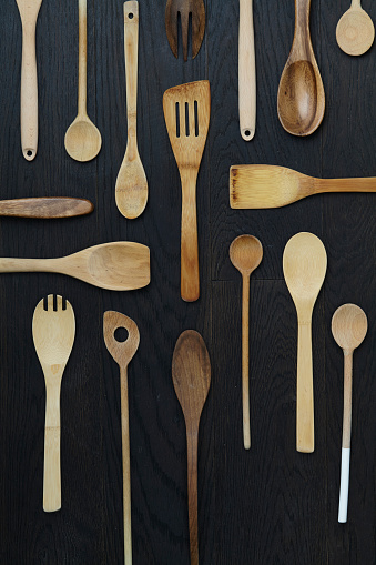 Variety of wooden spoons for cooking on a dark rustic wooden kitchen table, top view with a copy space