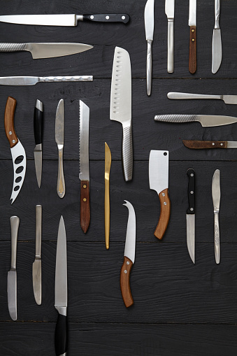 Variety of kitchen knives on a rustic wooden table, top view with a copy space