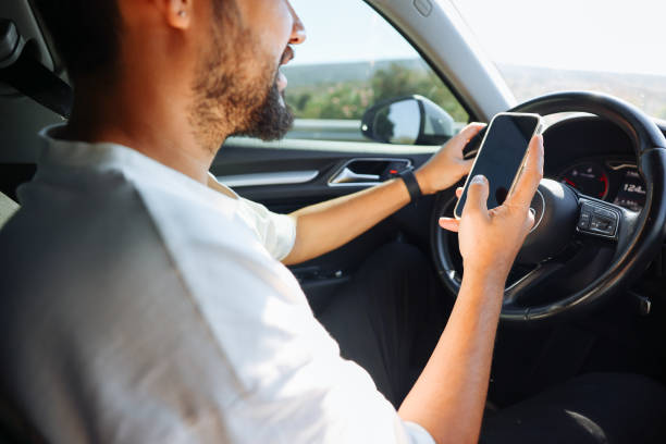 istock Young man in car checking his smartphone while driving 1416437257