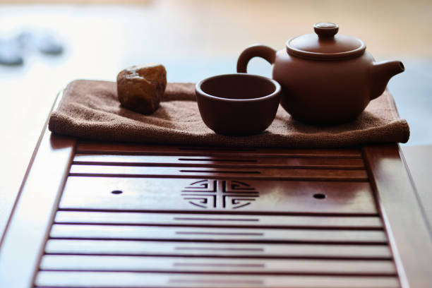 A serene outdoor scene featuring a glass teapot filled with vibrant red herbal tea and an empty glass cup placed on a wooden table. The blurred green background adds a sense of tranquility, making this image ideal for themes related to tea culture, relaxation, and healthy beverages
