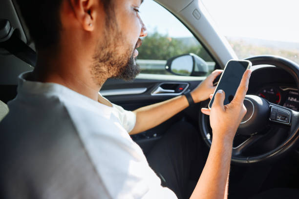 istock Young man in car checking his smartphone while driving 1416437312