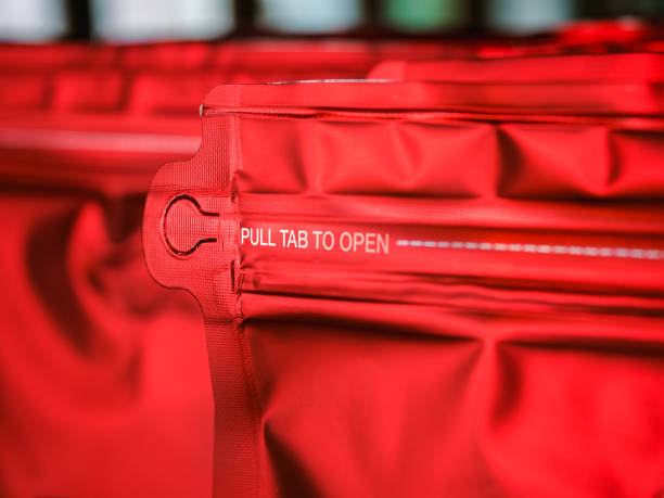 istock Closeup white message pull tab to open and dash dotted line for tear near the zip on red coffee bag, vivid foil paper zipper pouch packaging. 1416437476