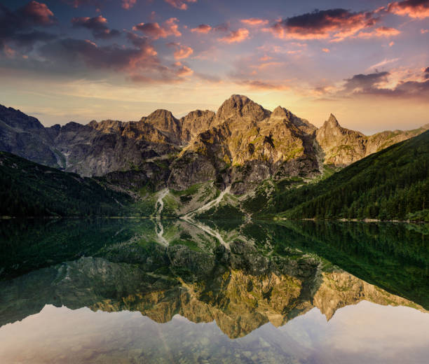 Amazing landscape of Tatra Mountains at sunset. View of  high rocks, illuminated peaks and stones, reflected in mountain lake (Morskie Oko). The concept of awakening and harmony with nature. stock photo