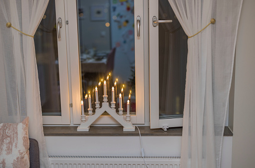 Beautiful view of window with white curtains and traditional advent lamp.