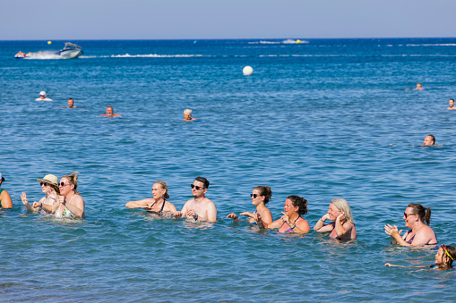 Rhodes. Greece. 07.15.2022.  View of group of tourists doing water dancing in on coastline of Mediterranean sea.