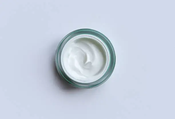 White cream jar on soft pastel blue background close-up. Beauty cosmetics presentation. Moisturizing skincare product. Top view. Trendy healthcare concept. Copy space for design. Flat lay style