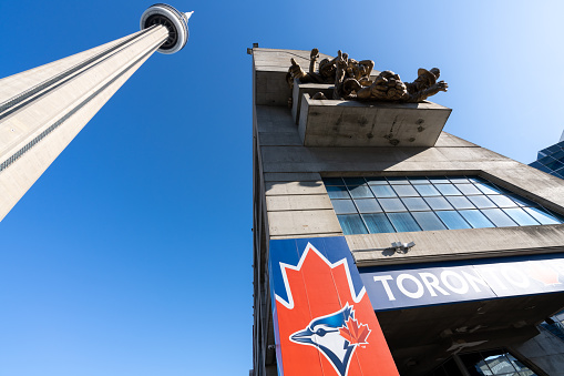 Toronto, ON, Canada - July 10 2021 : CN Tower and Rogers Centre spectator sculpture against a blue sky background.