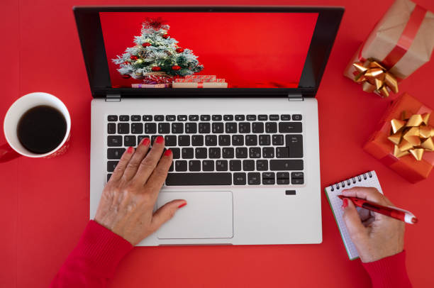 istock Woman's hands browsing on laptop at Christmas time - red background with Christmas presents 1416451954