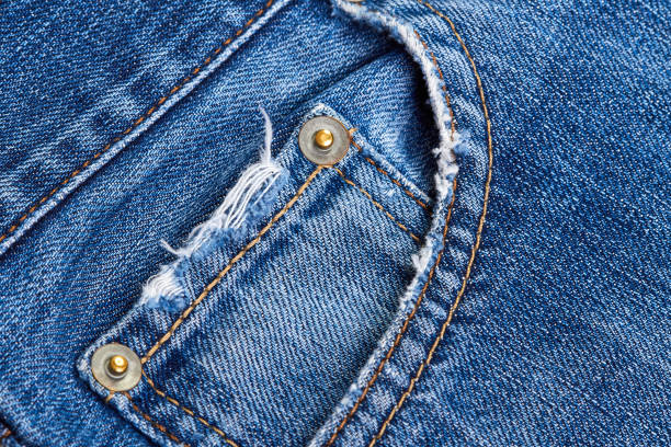 a blue denim jeans pocket with damages, seams, rivets and orange thread stitches - embroidery needlecraft product composition canvas imagens e fotografias de stock