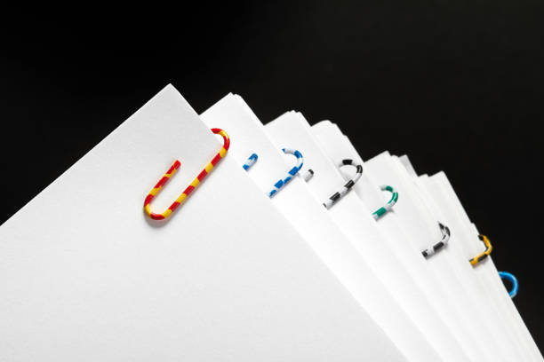 Stacks of papers with multicolored paper clips on a dark background
