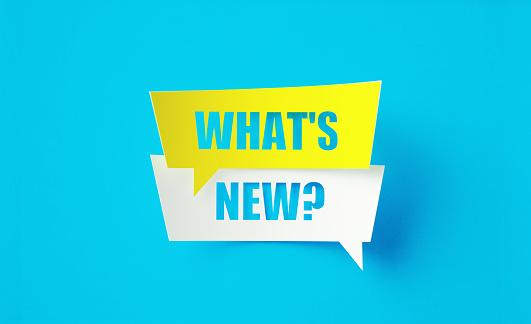 What's New written cut out yellow and white speech bubbles sitting on blue background. Horizontal composition with copy space.