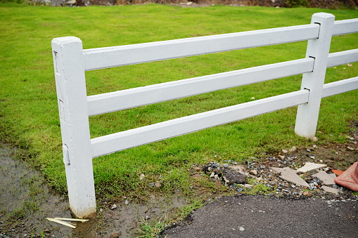 Closeup of white picket fence for horses on farm estate grounds in Virginia countryside with nobody in spring or autumn during sunny day