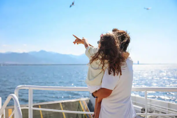 Photo of Girl traveling by ship with her father and looking seagull