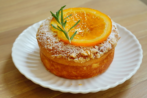 Portion of homemade testy vanilla orange date upside down cake made from almond meal, eggs, dates and orange slices on the top and a drizzle orange syrup