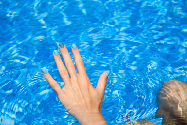 istock Female hands with bright manicure inside of water 1416472278