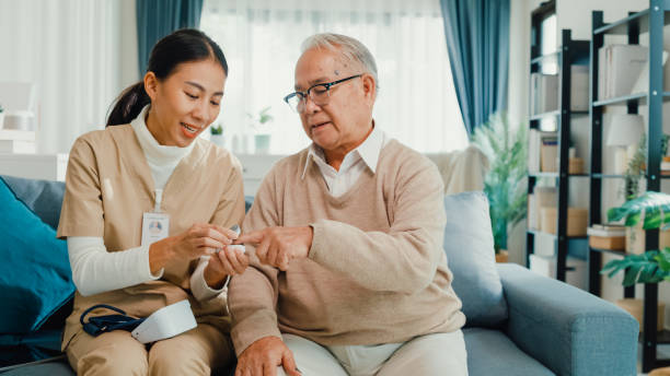 Young Asian female personal caregiver take care older men use fingertip pulse oximeter check blood oxygen pressure in living room at house. Young Asian female personal caregiver take care older men use fingertip pulse oximeter check blood oxygen pressure in living room at house. Mature male patient in nursing home, Healthcare concept. medical oxygen stock pictures, royalty-free photos & images
