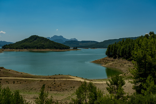 Woodland. Clear sky. There are many forested lakes around. Areas close to the lake are shaved from vegetation.