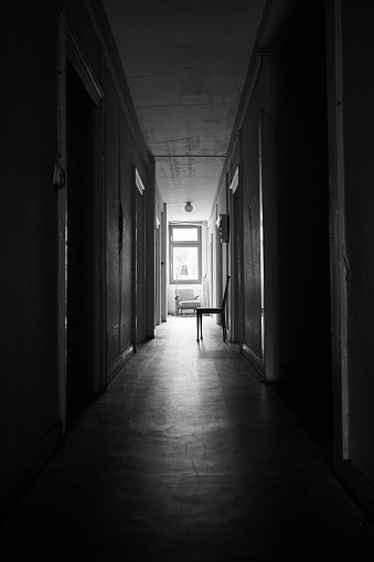 Bright sunlight shines through distant window in a dark and spooky hallway. Spooky corridor.