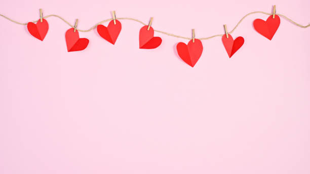 istock Creative hearts hanged on rope on pastel pink copy space background. Creative Valentine's day concept 1416488116