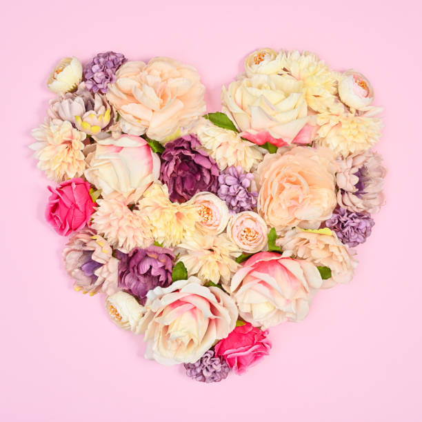 istock Heart shape made with natural spring flowers on pastel pink background. Flat lay 1416490253