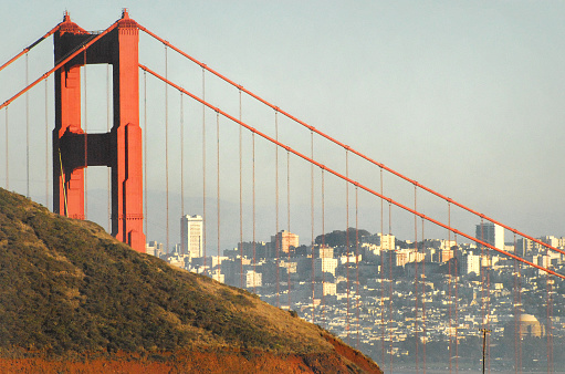 A beautiful close up of the Golden Gate bridge with the city of San Francisco in the background, at sunset.