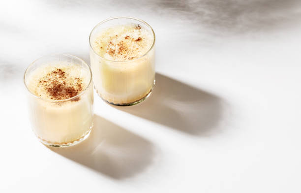 istock Two glasses with Christmas eggnog with cinnamon on white with beautiful shadows. Selective focus. 1416494075