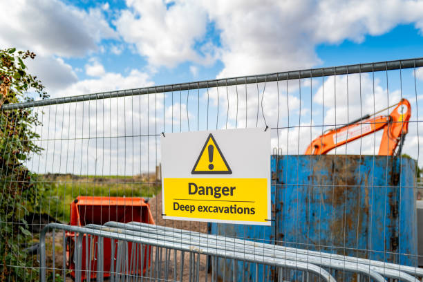 Generic yellow triangle warning sign describing Deep Excavations at a pipeline laying site. Generic yellow triangle warning sign describing Deep Excavations at a pipeline laying site. Beyond the fence its a 20ft deep hole which poses a hazard to the public. hazard sign stock pictures, royalty-free photos & images