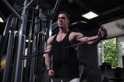 Strong muscular male athlete training with resistance band