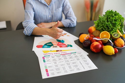 nutritionist makes a tick sign in front of the healthy eating menu she has prepared