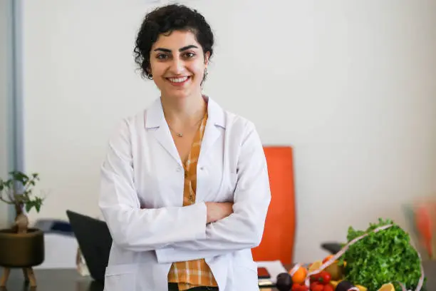 portrait of young beautiful healthy nutritionist with arms folded