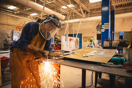 A young teenage high school female is practicing her welding skills while at school. She is working in her high school shop class. Image taken on the Navajo Reservation, Utah, USA.