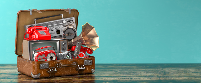 Vintage electrical and electronic appliances in an old suitcase. Nostalgic retro objects from the past 1960s - 1980s on green backgound. 3d illustration