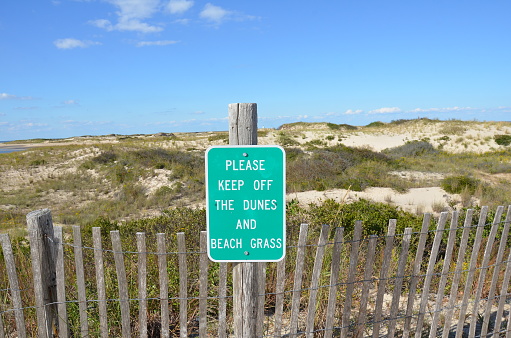 wood fence and sand dunes at the beach or coast with please keep off sign