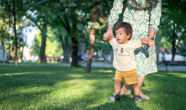 istock One year old making his first steps in the park with the help of his mom 1416518531