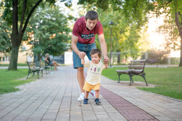 istock One year old making his first steps in the park with the help of his father 1416518917