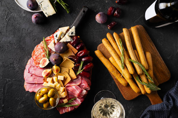 istock Meat, cheese and snackes plate, board and grissini on black background 1416538092