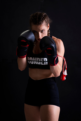 Portrait of young woman practicing muay thai in gym.