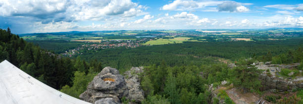 Panoramic view from hill Topfer sandstone viewpoint near Oybin with view of Zittau town at Poland German borders in Zittauer Gebirge mountains, Saxony, germany. Summer sunny day, blue sky, white clouds. vista panorámica desde el mirador de arenisca de la colina topfer cerca de oybin con vista de la ciudad de zittau en polonia fronteras alemanas en las montañas zittauer gebirge, sajonia, alemania. día soleado de verano, cielo azul, nubes blancas