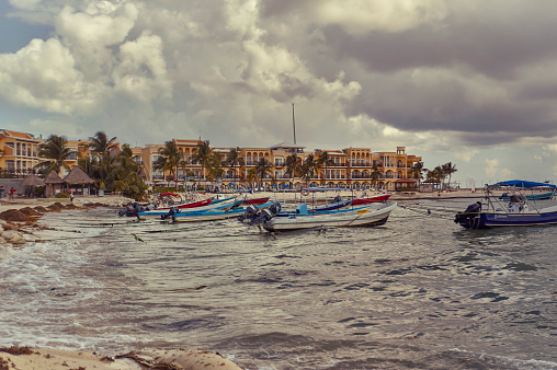 Panorama depicting Small fishing boats moored in the rough sea of Playa del Carmen beach in Mexico on the Mayan Riviera on a cloudy day.