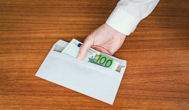 A white envelope with Euro money bills is handed over by a hand. stock photo