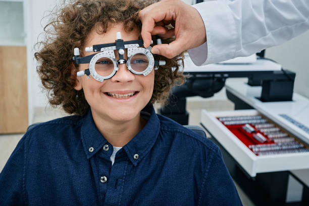 istock Optometrist selecting eyeglass lenses for cute boy using optometrist trial frame and lenses at ophthalmology clinic. Children's vision test 1416553813