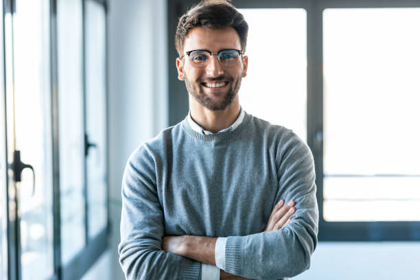 istock Smart handsome business man standing while crossing arms looking at camera in a modern startup. 1416554106