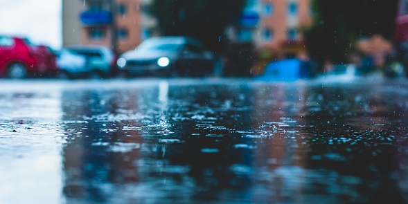 Raindrops on asphalt. Rain. Rainy weather. Car on the road. Evening twilight