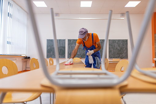 Man wiping a surface while spraying it with product