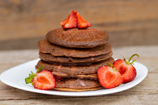 chocolate pancakes with strawberries on a white plate