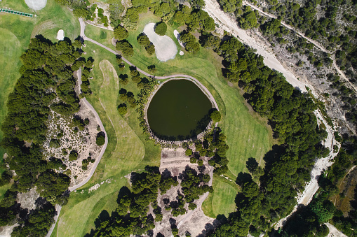 Aerial view from above golf course with lush green fields and lake during a sunny summer day, no people. Nature background, recreation outdoor concept. Costa Blanca. Spain