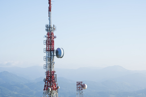 Communications and data transmission antennas with the blue sky and mountains in the background.
