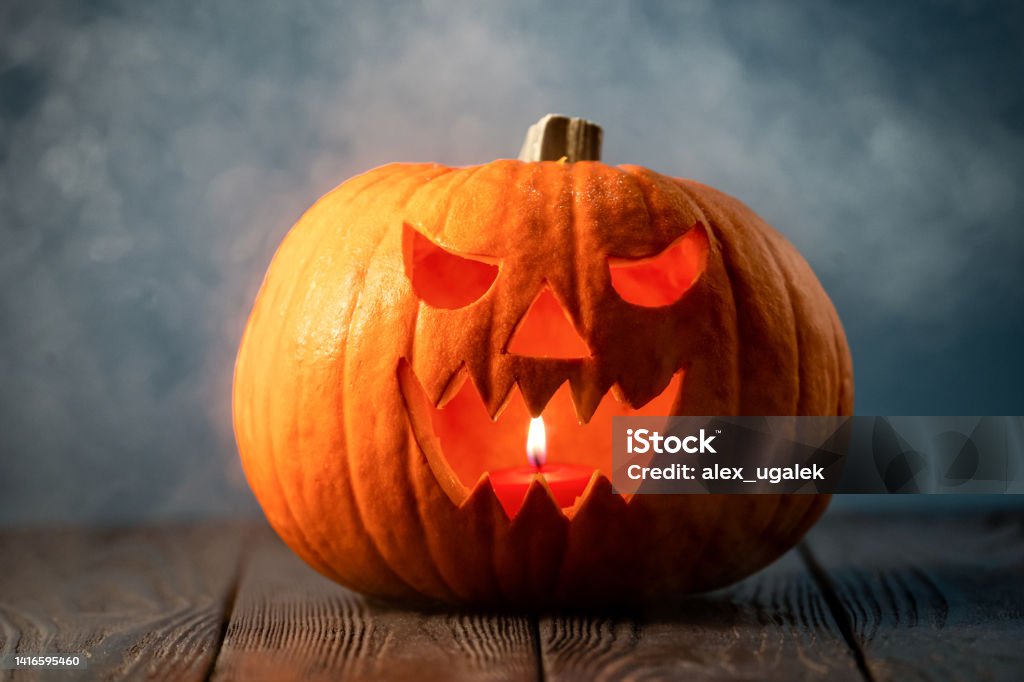 Jack-o-lantern in smoke Jack-o-lantern in smoke on black table. Creepy pumpkin for Halloween illuminated with candle. Halloween scary background. Jack O' Lantern Stock Photo