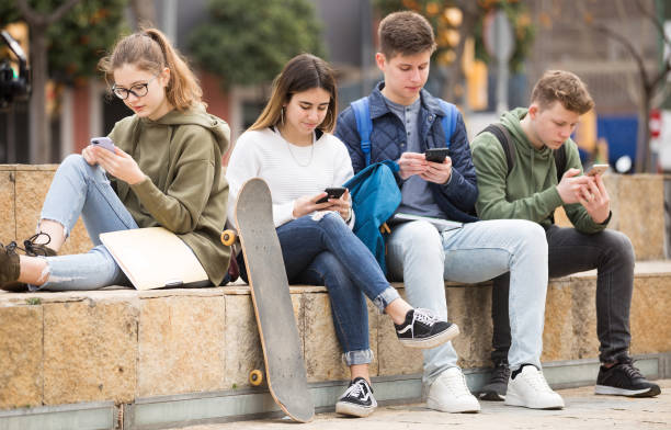 Teenagers chatting on their smartphone on walking stock photo