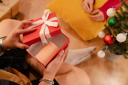 Young Asian couple in seasonal costume decorating the Christmas tree  in the living room together and enjoying their Christmas.